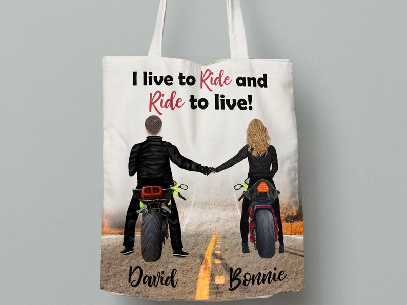 Pu&ograve; includere: Borsa tote bianca con un'illustrazione in bianco e nero di una coppia in moto. Il testo "I live to Ride and Ride to live!" &egrave; stampato in rosso sulla borsa. I nomi "David" e "Bonnie" sono stampati sotto la coppia.