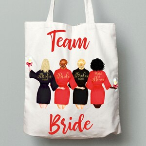 Pode incluir: Sacola de lona branca com o texto "Team Bride" em letras vermelhas. Quatro mulheres em roup&otilde;es s&atilde;o retratadas segurando ta&ccedil;as de champanhe. Os roup&otilde;es s&atilde;o pretos, vermelhos e vermelhos com texto dourado que diz "Bridesmaid", "Bride", "Bridesmaid" e "Maid of Honor".