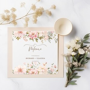 May include: A wedding welcome sign with a floral design in shades of pink and green. The sign says "Welcome to the wedding of Richard and Claudia, 21 January 2023".