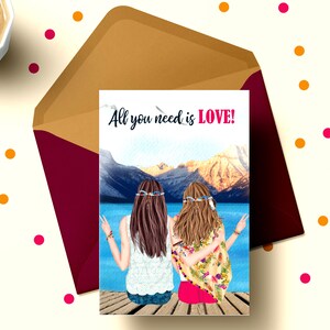 May include: A greeting card with a watercolor illustration of two women with long hair wearing flower crowns and sitting on a dock overlooking a lake and mountains. The text on the card reads "All you need is LOVE!"