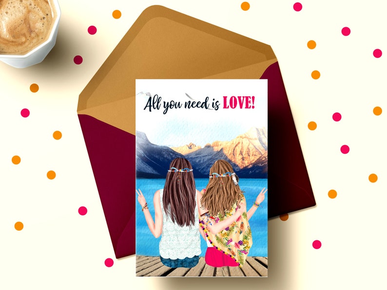 May include: A greeting card with a watercolor illustration of two women with long hair wearing flower crowns and sitting on a dock overlooking a lake and mountains. The text on the card reads "All you need is LOVE!"