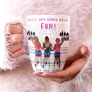 Peut inclure: Mug en c&eacute;ramique blanche avec une illustration color&eacute;e de trois femmes assises &agrave; un comptoir de bar. Le mug porte l'inscription "Girls just wanna have FUN!" en haut et les noms "Lola, Mila, Alicia" en bas.