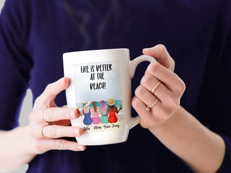 May include: White ceramic mug with a colourful illustration of four women on the beach. The text "Life is better at the beach!" is printed on the mug. The names "Lola, Nina, Sam, Jenny" are printed below the illustration.