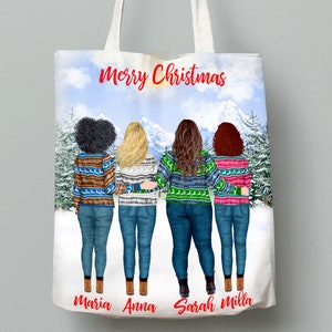May include: A white tote bag with a winter scene featuring four women wearing colorful sweaters and jeans. The text "Merry Christmas" is printed in red at the top of the bag. The names "Maria", "Anna", "Sarah", and "Milla" are printed at the bottom of the bag.