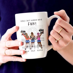 Peut inclure: Mug en c&eacute;ramique blanche avec une illustration en noir et blanc de trois femmes dans un bar avec le texte "Girls just wanna have FUN!" et les noms "Lola, Mila, Alicia" imprim&eacute;s sous l'illustration.