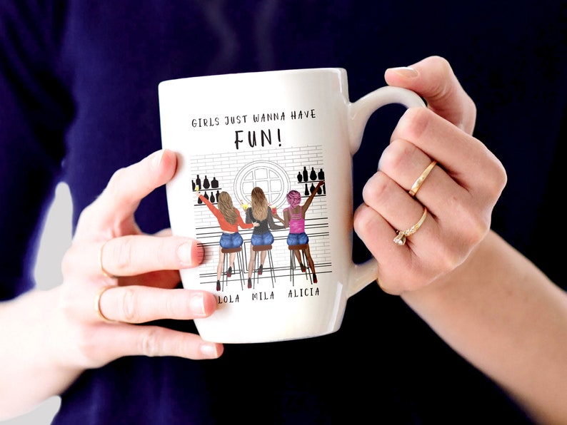 Peut inclure: Mug en c&eacute;ramique blanche avec une illustration en noir et blanc de trois femmes dans un bar avec le texte "Girls just wanna have FUN!" et les noms "Lola, Mila, Alicia" imprim&eacute;s sous l'illustration.