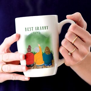 May include: White ceramic mug with a green mountain scene and three women standing in front of it. The mug says "Best Granny ever" and has the names "Hilla, Audra, Sarah" at the bottom.