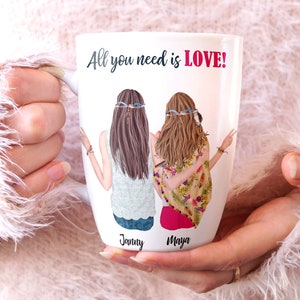 May include: White ceramic mug with a graphic of two women with long hair wearing headbands. The text "All you need is LOVE!" is printed on the mug. The names "Janny" and "Maya" are printed below the women.