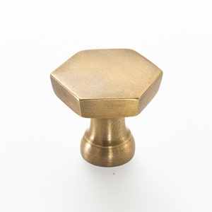 May include: A hexagonal brass cabinet knob with a rounded base.