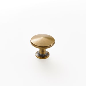 May include: A single, antique brass cabinet knob. The knob has a rounded top and a short, cylindrical base. The finish is a warm, aged brass color, suggesting a vintage or rustic aesthetic. The knob is designed for use on drawers or cabinet doors.