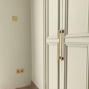 May include: A white closet door with two gold-toned handles. The door has a raised panel design.