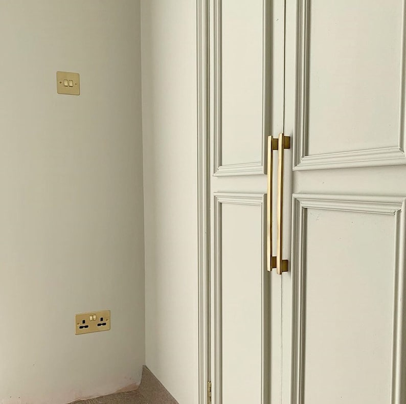 May include: A white closet door with two gold-toned handles. The door has a raised panel design.
