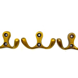 May include: Three gold-toned metal double hooks. Each hook has two prongs that curve upward.
