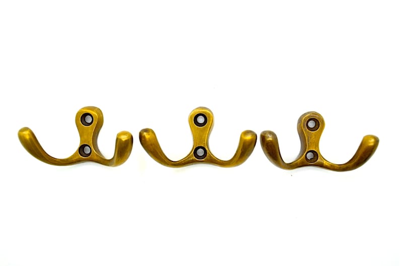 May include: Three gold-toned metal double hooks. Each hook has two prongs that curve upward.