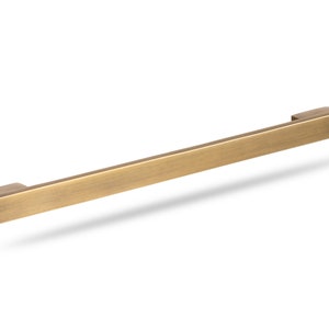 May include: A brushed gold cabinet pull with a rectangular shape.