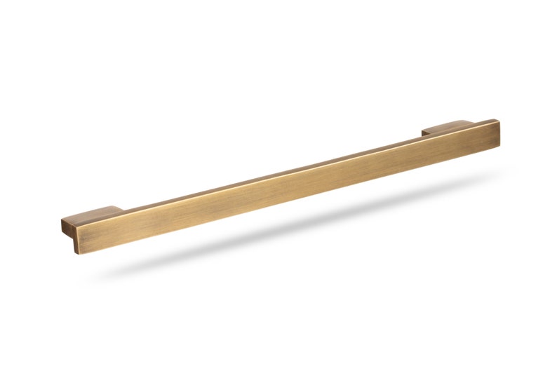 May include: A brushed gold cabinet pull with a rectangular shape.