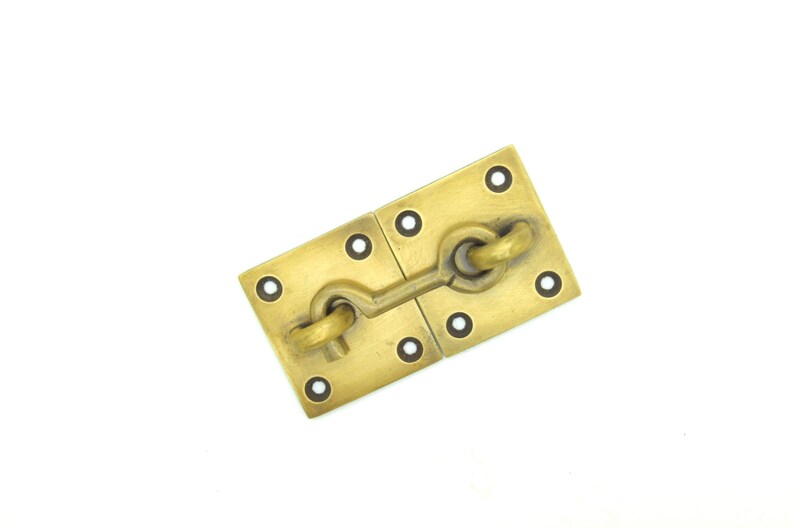 May include: Brass door latch with a hook and eye design. The latch is attached to two square plates with four holes each.