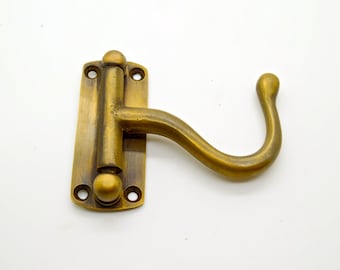 May include: A brass hook and latch set with a curved hook and a rectangular plate with two round knobs. The hook and latch are in a polished brass finish.