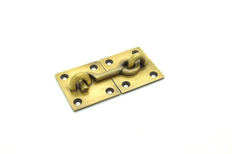 May include: A brass door latch with a square plate and a hook-shaped latch. The latch is attached to the plate with a screw.