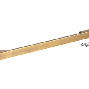 May include: A brushed brass cabinet pull with a rectangular shape and rounded edges. The pull comes with two screws for installation.