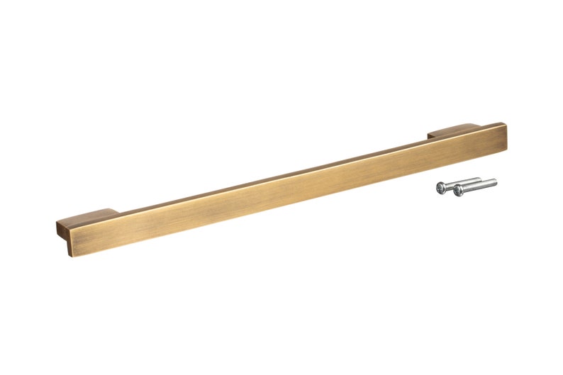 May include: A brushed brass cabinet pull with a rectangular shape and rounded edges. The pull comes with two screws for installation.