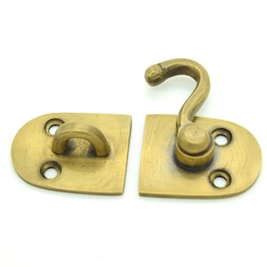 May include: A brass hook and latch set for a door or cabinet. The hook has a rounded knob and the latch has two holes for screws.