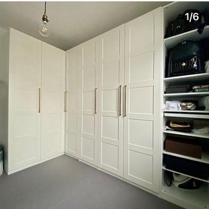 May include: A set of white closet doors with gold handles. The doors are arranged in a corner and have a simple, modern design.