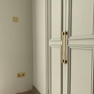 May include: A white closet door with two gold metal handles. The door has a raised panel design.