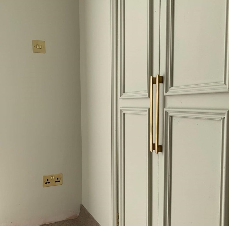 May include: A white closet door with two gold metal handles. The door has a raised panel design.