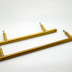 May include: Two gold metal cabinet door pulls with a brushed finish. The pulls are approximately 10 inches long.