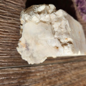 May include: A white, opaque, rough-textured crystal with a smooth, translucent section. The crystal has a natural, raw appearance.