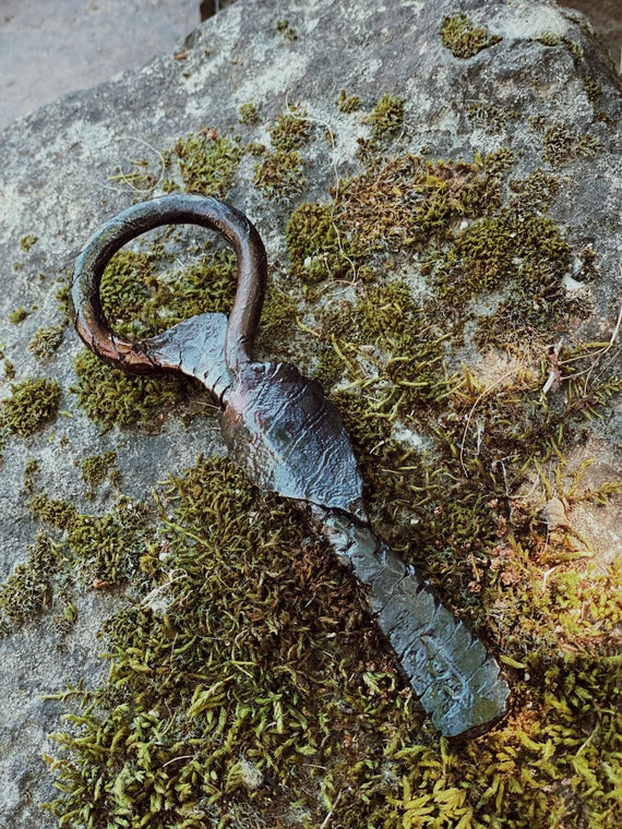 A blacksmith actually hammered this bottle opener into a leaf shape — it's a tiny piece of functional forged iron art that most people have never held.