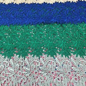 May include: Four different lace trims in beige, blue, green, and gray. The lace trims have a floral pattern.