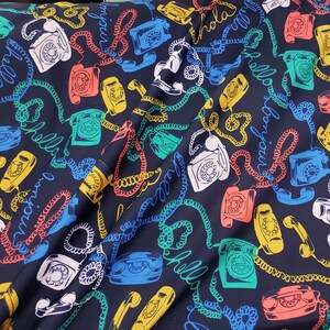 May include: A dark blue fabric with a repeating pattern of rotary phones, colorful cords, and the words "hello", "bonjour", and "hola".