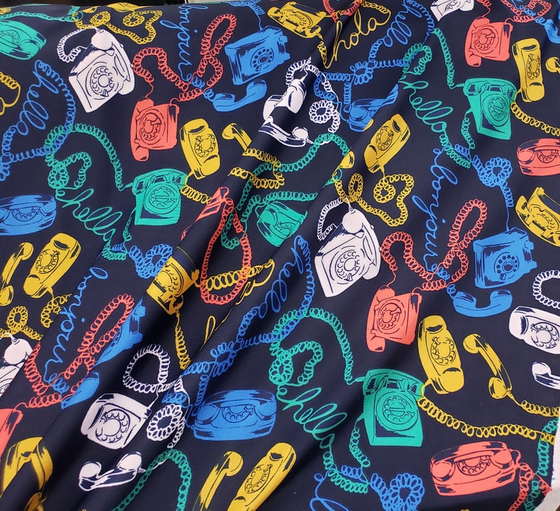May include: A dark blue fabric with a repeating pattern of rotary phones, colorful cords, and the words "hello", "bonjour", and "hola".