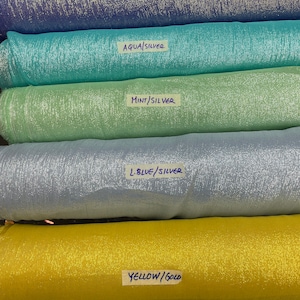 May include: Five rolls of fabric with different colors and metallic finishes. The fabric rolls are labeled with the colors "Royal/Gold", "Aqua/Silver", "Mint/Silver", "L.Blue/Silver", and "Yellow/Gold".