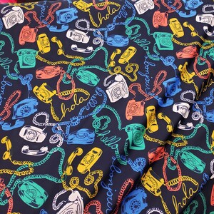 May include: A dark blue fabric with a repeating pattern of vintage rotary phones, colorful cords, and the words "Hola", "Bonjour", and "Hello" in a variety of colors.