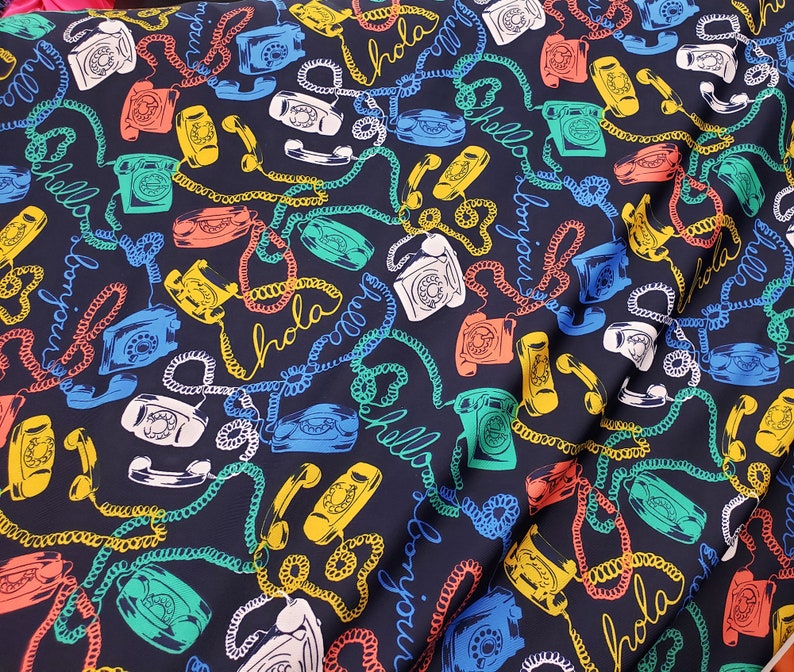 May include: A dark blue fabric with a repeating pattern of vintage rotary phones, colorful cords, and the words "Hola", "Bonjour", and "Hello" in a variety of colors.