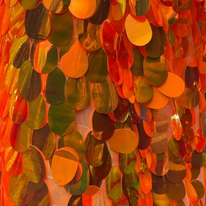 May include: Orange iridescent sequins on a sheer mesh fabric. The sequins are arranged in a scale-like pattern.