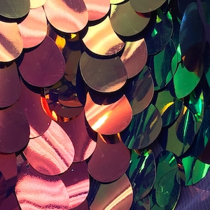 Pode incluir: Close-up de lantejoulas iridescentes em tons de vermelho, verde e dourado dispostas em um padrão de escamas de peixe.