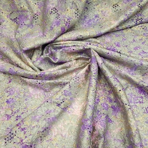 May include: A close-up of a fabric with a metallic gold and purple pattern. The fabric has a textured surface and a subtle sheen.