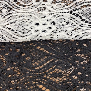 May include: Two pieces of lace fabric, one white and one black. Both pieces have a delicate, intricate pattern.