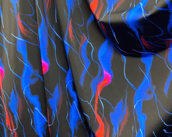 May include: Black fabric with a vibrant abstract design. The pattern features flowing strokes of blue, red, and pink, creating a dynamic and colorful visual effect. The fabric is draped, showcasing the fluidity of the material.