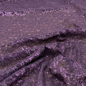May include: Purple lace fabric with a glittery finish. The lace has a delicate floral pattern.
