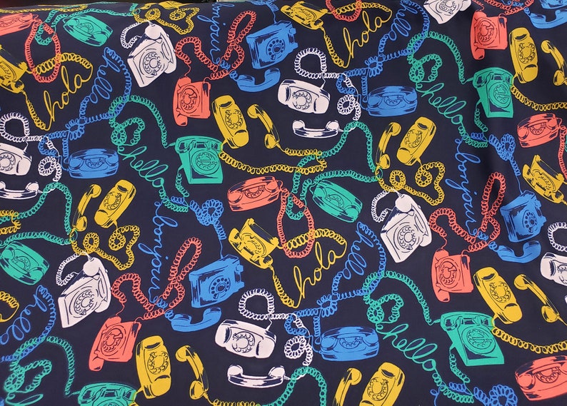 May include: A dark blue fabric with a repeating pattern of colorful rotary phones and the words "hola", "hello", "bonjour" and "bonjour".