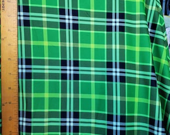 May include: Green fabric with a plaid pattern featuring black, white, and light green stripes.