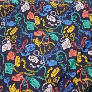May include: A dark blue fabric with a repeating pattern of vintage rotary phones, colorful phone cords, and the words "Hola", "Bonjour", and "Hello" in different languages.