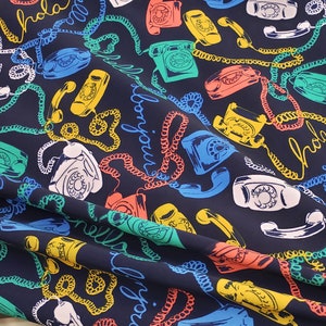 May include: A dark blue fabric with a repeating pattern of colorful rotary phones and the words "Hola", "Bonjour", and "Hello" in a variety of colors.