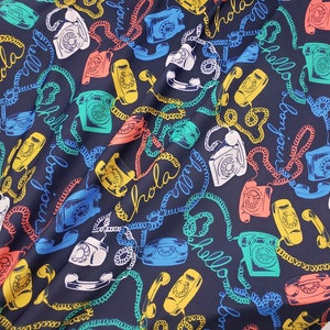 May include: A dark blue fabric with a repeating pattern of colorful rotary phones, phone cords, and the words "Hola", "Hello", and "Bonjour".