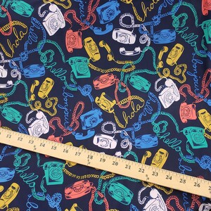 May include: A dark blue fabric with a repeating pattern of colorful rotary phones and the words "Hola", "Bonjour", and "Hello" in a white, yellow, and red font.